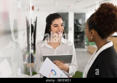 Deux femmes discutant des résultats présentés sur tablette et documents Banque D'Images