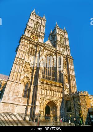 La grande entrée de l'abbaye de Westminster, avec ses tours jumelles et son design gothique élaboré, capturée sous la lumière du soleil Banque D'Images