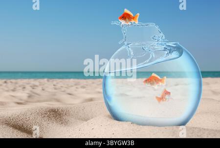 Poisson rouge sautant hors d'un bol de poisson en verre contre la mer à la plage Banque D'Images