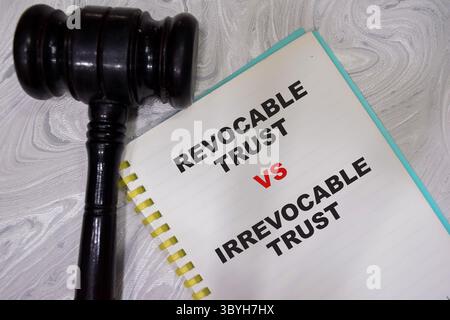 Concept de confiance révocable VS confiance irrévocable écrire sur le livre avec le marteau isolé sur la table en bois. Banque D'Images