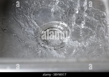L'eau du robinet s'écoule dans l'évier. L'eau s'écoule dans l'évier. Banque D'Images