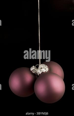 trois boules violettes se transportant en fil d'argent sur noir Banque D'Images