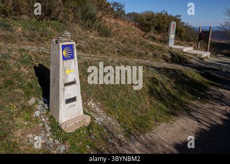 O Cebreiro, Espagne. Camino de Santiago jalon avec coquille de Saint-Jacques jaune et flèche indiquant les kilomètres restants à Santiago de Compostelle sur un rur Banque D'Images