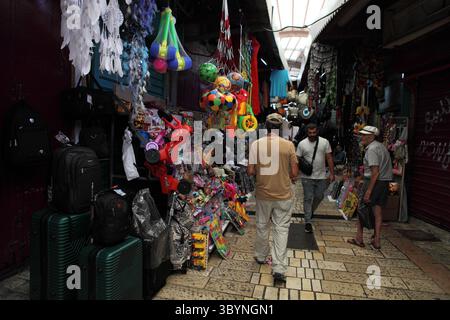 Akko ou Acre, magasin de jouets dans une vieille ville du 18ème siècle marché ottoman avec des passants, diverses pièces de marchandises accrochées devant le magasin. Banque D'Images