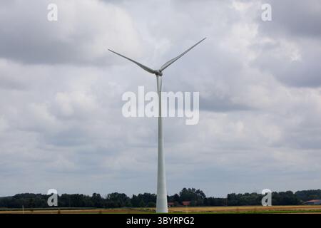 Une seule éolienne s'élève majestueusement au-dessus du polder néerlandais plat sous un ciel sombre, symbolisant la fusion de l'ingénierie moderne et de l'énergie durable ! Banque D'Images