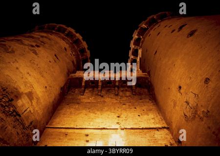 le fort médiéval domine « Torres de Quart » avec des prises de vue de canon visibles dans la nuit illuminée d'orange à Valence, Espagne Banque D'Images