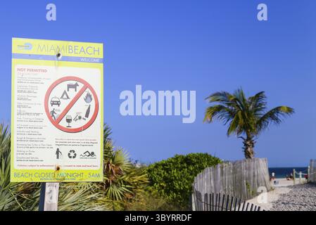 Miami Beach, États-Unis - 9 mai 2015 : un panneau d'interdiction montrant les activités interdites sur la plage avec une entrée à la plage dans le dos, Miami Banque D'Images