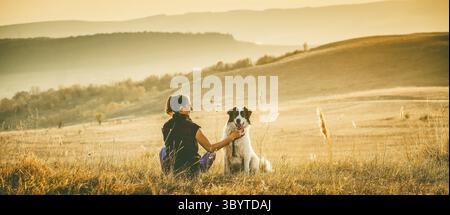 Femme avec chien se détendre dans le paysage d'automne Banque D'Images