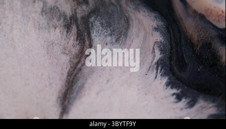 Texture éclaboussure. Dispersion de particules d'encre. Défocalisé couleur blanc orange liquide brillant goutte à goutte mouillé flottant sur fond d'art noir foncé. Banque D'Images