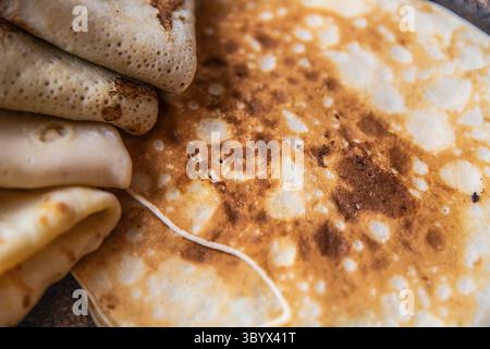 Vue macro de crêpes minces présentant des cloques brunes dorées et une texture douce, parfaite pour les arrière-plans, le stylisme alimentaire et les concepts de design culinaire. Banque D'Images