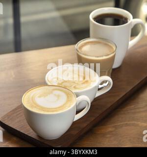 Différents types de café dans des tasses sur un fond en bois, cappuccino, americano, latte macchiato Banque D'Images