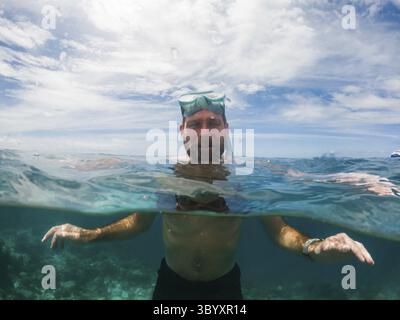Homme snorkeling dans la mer tropicale cristalline Banque D'Images