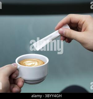 Homme versant du sucre dans le café latte Banque D'Images