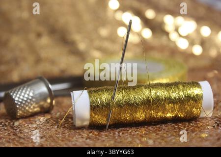 Sequins dorés sur tissu avec bobine de fil métallique doré et de Thimble Banque D'Images