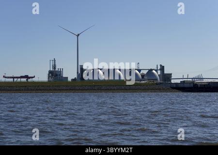 Vue sur l'Elbe jusqu'à la station d'épuration de Hambourg avec ses tours de digestion en acier inoxydable en forme de poing caractéristiques, à côté d'un grand wi Banque D'Images