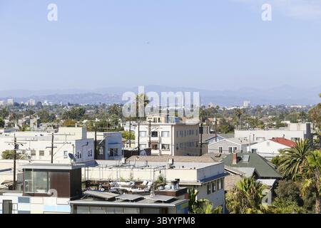 Vue sur les toits avec quelques terrasses de toit vers les montagnes de Santa Monica à l'horizon brumeux. En face, il y a la skyline de Century City avec Banque D'Images