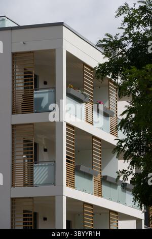 Détail architectural d'un immeuble résidentiel moderne. La façade blanche dispose de plusieurs balcons empilés avec balustrades en verre dépoli et Banque D'Images