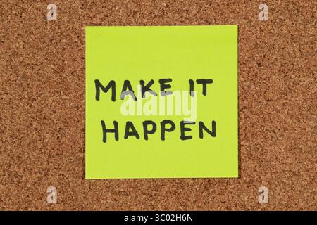 Gros plan sur une note autocollante avec une phrase de motivation positive « Make It Happen » sur un fond de liège Banque D'Images