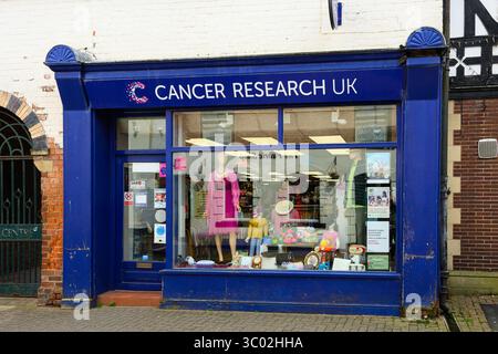 Newtown, pays de Galles, Royaume-Uni - 29 mars 2025 ; cancer Reasearch UK avant de la boutique caritative sur la rue avec des marchandises à vendre Banque D'Images
