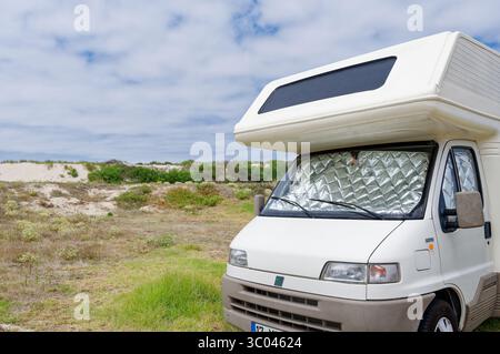 Camping-car garé le long des dunes de sable, protégeant l'intérieur du soleil avec des couvertures réfléchissantes Banque D'Images