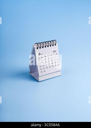 Juin, 2025 année page de calendrier de bureau, organisateur pour planifier et rappeler debout isolé sur fond vertical bleu, style minimal. Petite table blanche Banque D'Images