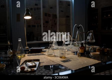 Un laboratoire dispose de divers flacons en verre et équipements disposés sur une table, éclairés par une lampe, mettant en valeur un environnement d'exploration scientifique A. Banque D'Images