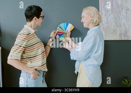 Les femmes discutent des nuances de couleur contre le mur gris Banque D'Images