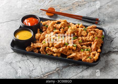 Sichuan Pepper Studded Crispy Pork Xiaosurou gros plan sur l'assiette sur la table. Horizontal Banque D'Images