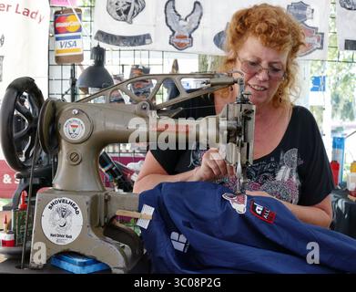 15 octobre 2018 - New Port Richey, Floride, États-Unis - MICHELE MILLER | TIMES.Eilleen Ceder, aka, ''The Slipper Lady'' coud un écusson de moto indienne sur un brise-vent pour un client au Cotee River Bike Fest, tenu du 12 au 14 octobre, dans le centre-ville de New Port Richey. .''je réussis généralement assez bien à la fête du vélo, a déclaré Ceder, 59 ans, qui offre un service spécialisé en étant capable de coudre des patchs sur place, en utilisant quelques machines à coudre à pédales antiques (crédit image : © Michele Miller/Tampa Bay Times via ZUMA Wire) Banque D'Images