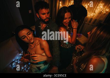 Amis célébrant un rassemblement d'anniversaire animé avec chanter et danser à la maison Banque D'Images