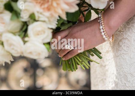 Main de mariée tenant bouquet avec anneaux et Bracelet de perles Banque D'Images