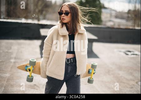 Femme élégante avec Skateboard sur Sunny Day Banque D'Images