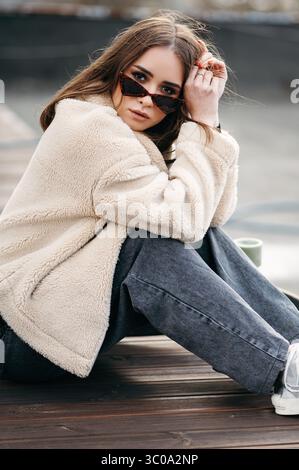 Femme à la mode dans des lunettes de soleil assis sur le toit Banque D'Images