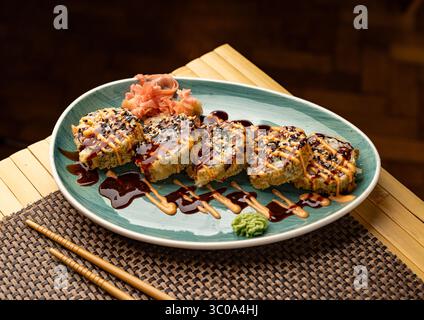 Rouleau de sushi frit chaud couché sur une assiette avec wasabi et gingembre Banque D'Images