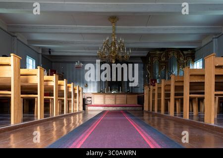 Intérieur de l'église de Käsmu en Estonie, bancs en bois, allée de tapis rouge, autel, lustre - architecture sacrée historique de la Baltique et atmosphère paisible Banque D'Images