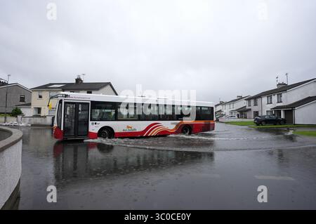 Un bus traverse les eaux de crue sur le Bay Estate à Dundalk, Co Louth, alors que des avertissements météorologiques orangés étaient en place pour certaines parties de l'Irlande après une nuit de fortes pluies sur l'île. Date de la photo : lundi 21 juillet 2025. Banque D'Images