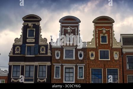 Maisons à pignons hollandaises traditionnelles bordant la rue du canal, patrimoine architectural reflétant le paysage urbain historique d'amsterdam sous ciel couvert Banque D'Images