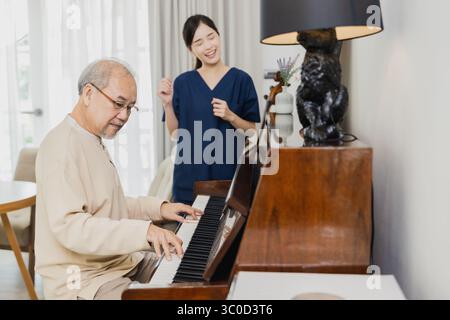 Jeune femme asiatique enseignant le piano pour l'enseignement de l'homme senior, fille heureuse et père âgé jouant du piano ensemble dans le salon à la maison Banque D'Images