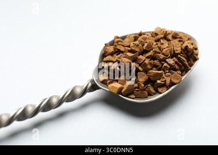 Cuillère avec café instantané granulé sur fond blanc, gros plan Banque D'Images
