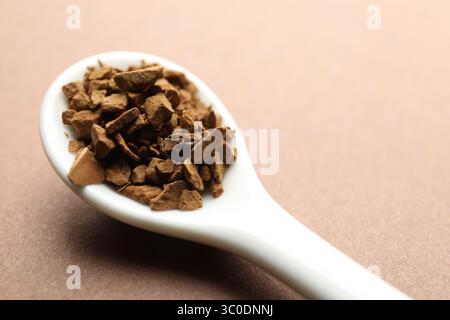 Cuillère avec café instantané granulé sur fond beige, gros plan Banque D'Images