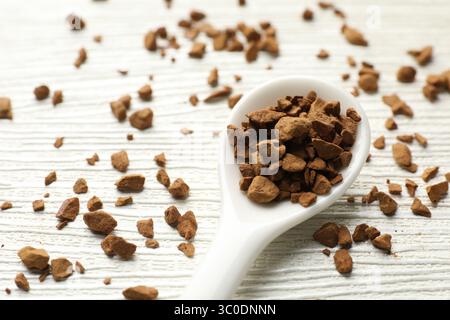 Cuillère avec café instantané granulé sur table en bois blanc, gros plan Banque D'Images