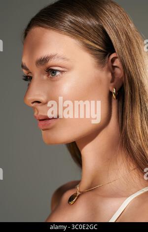 Une jeune femme présente sa peau bronzée et son maquillage naturel lors d'un tournage en studio d'été. Banque D'Images