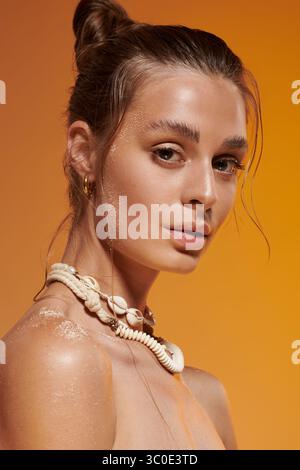 Une jeune femme à la peau bronzée présente la mode estivale dans un cadre de studio dynamique. Banque D'Images