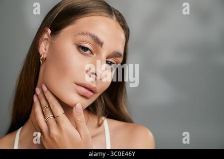Jeune femme avec la peau bronzée et le maquillage naturel met en valeur sa beauté dans un cadre de studio détendu. Banque D'Images