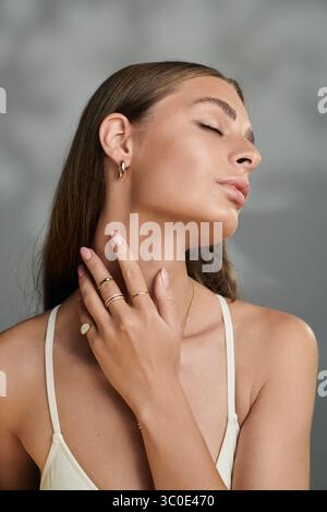 Une jeune femme à la peau bronzée présente un maquillage naturel tout en posant gracieusement dans un studio. Banque D'Images