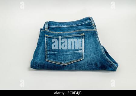 Paire unique de jeans bleus pliés et isolés sur fond gris. Banque D'Images