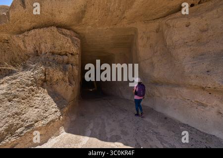 Femme randonneuse approchant de l'entrée d'un tunnel volcanique sculpté en carré à travers la roche de tuf Banque D'Images