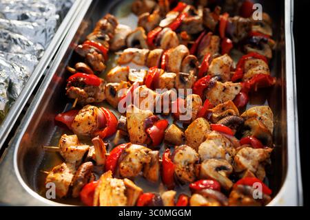 Plateau de brochettes de poulet grillé avec champignons, poivron rouge et assaisonnement. Tons chauds et texture huileuse. Banque D'Images