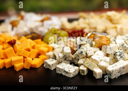 Assortiment de fromages en cubes avec raisins et fruits secs sur plateau Banque D'Images