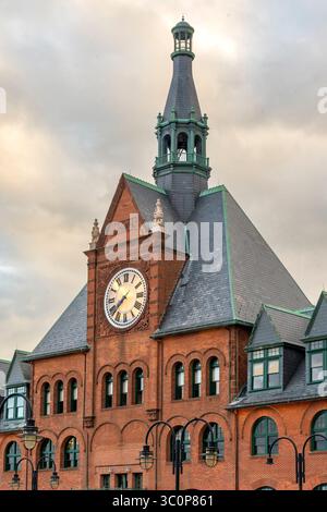 Jersey City, NJ - US - Jul 19, 2025 la tour de l'horloge en briques rouges du terminal CRRNJ s'élève sous un ciel sombre, sa face en chiffres romains et sa flèche au toit vert Banque D'Images